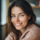 Femme souriante portant un pull en laine beige.